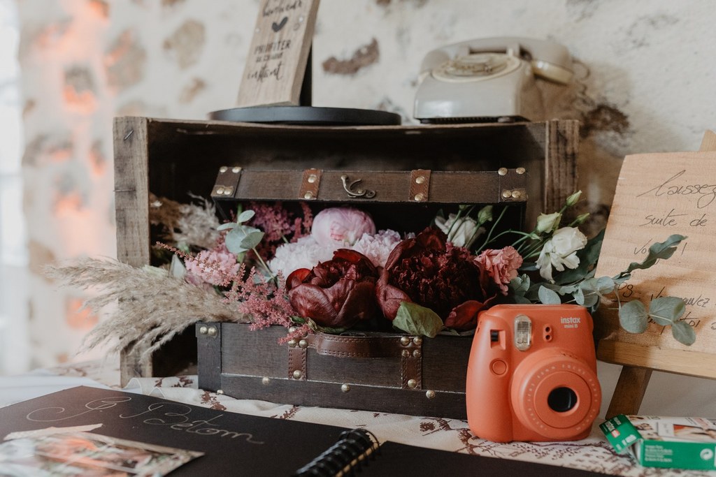 un photobooth créatif l'instax mini, appareil photo, valise, fleurs, pivoine, pancarte, urne, livre d'or mariage