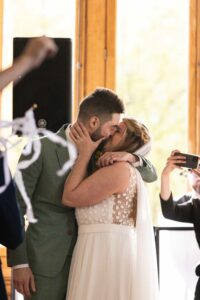 Sortie de Cérémonie Laïque. Les mariés s'embrassent à la fin de leur cérémonie laïque. Les invités utilisent des clochettes à ruban pour les féliciter.