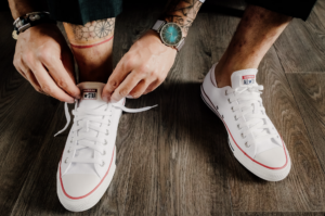 Se marier en basket. Préparatif du marié. Il est entrain de mettre ses baskets blanches personnalisées.